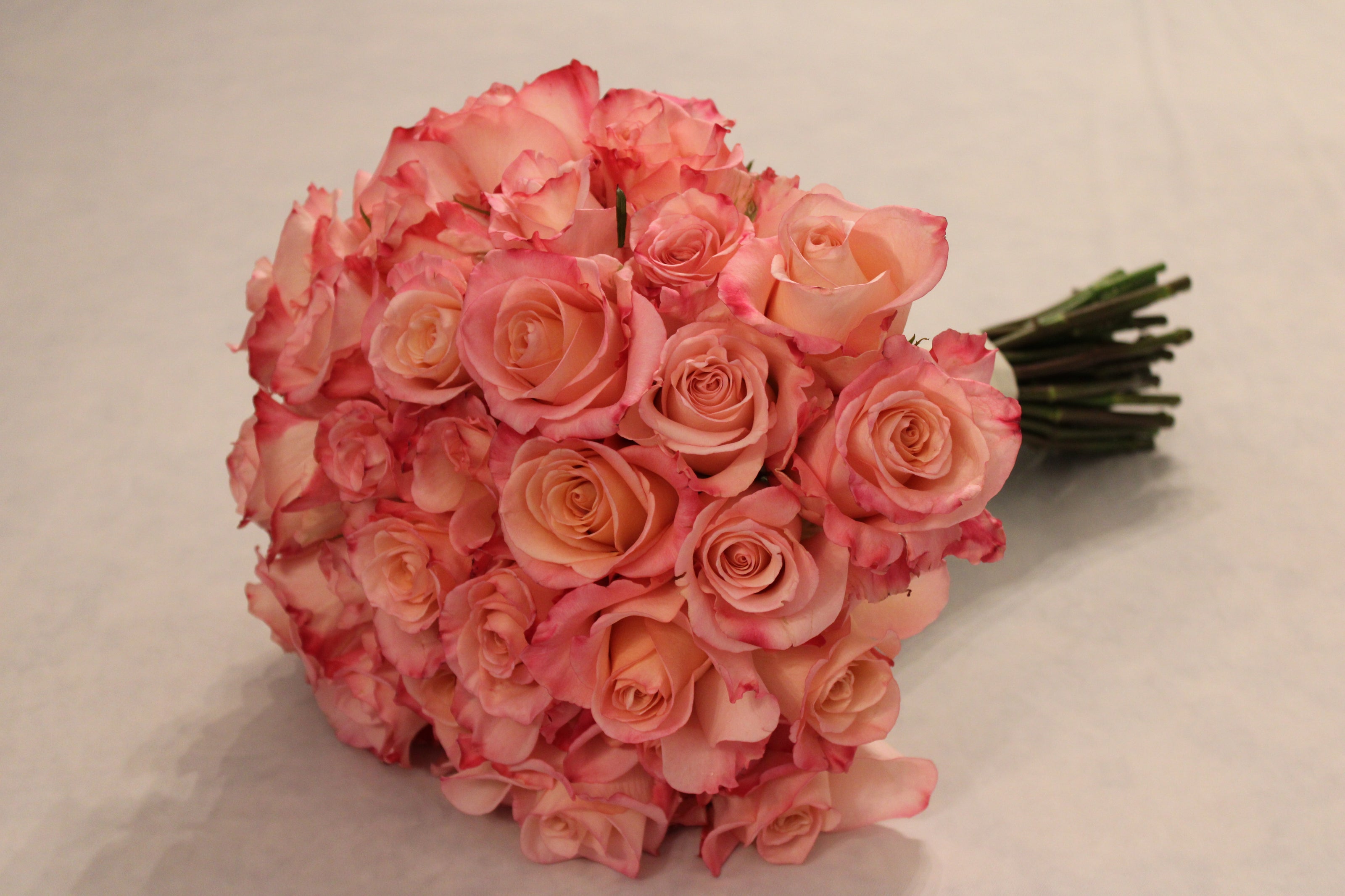 Proposal bouquet of pink Rhoslyn roses with coral and hot pink tones. Round, modern-style bouquet.