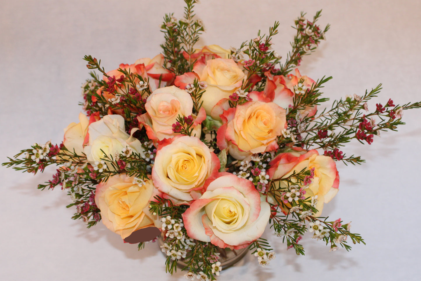 Beautiful spiral round flower arrangement with cabaret roses and pink and white wax flower