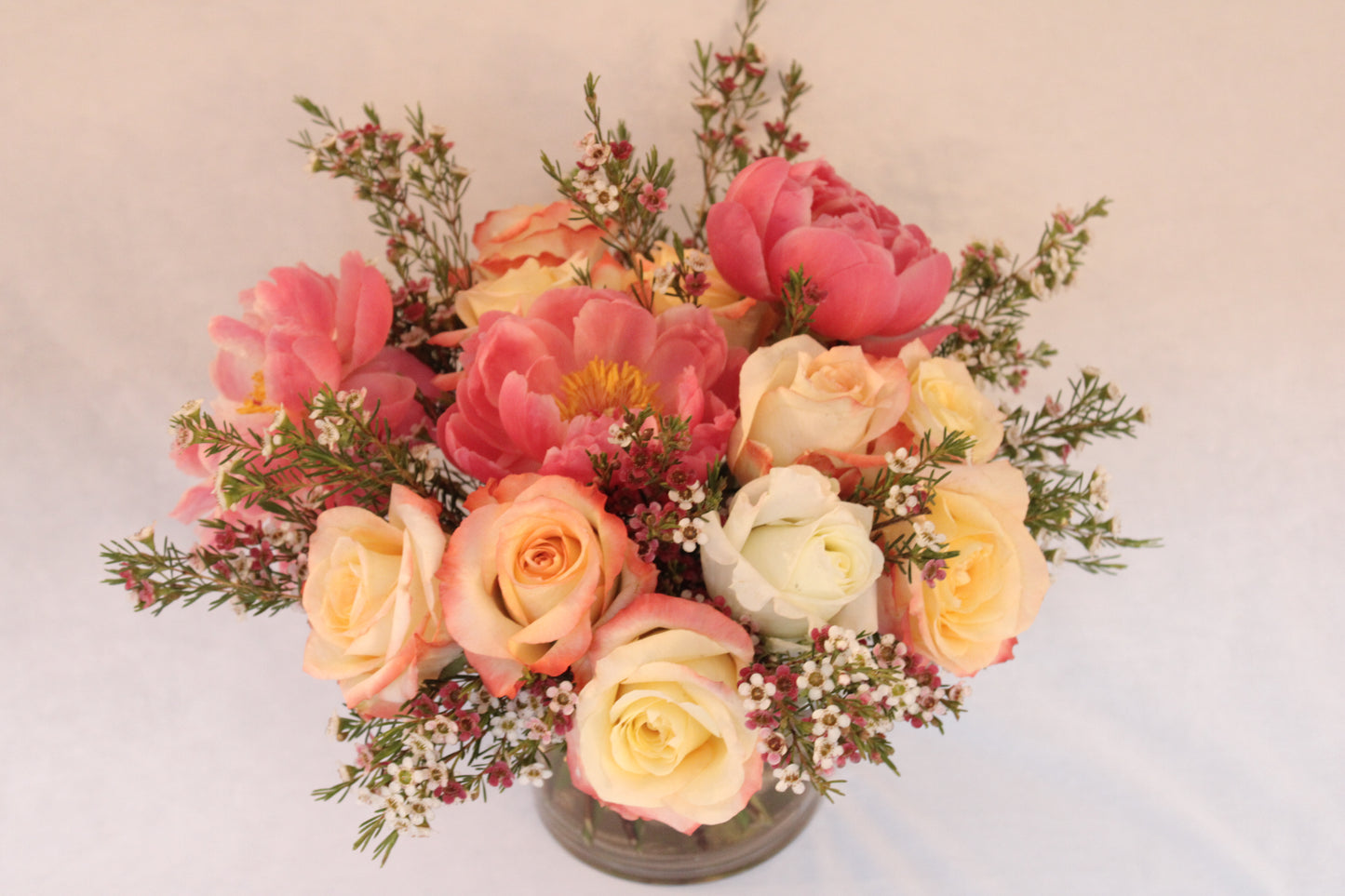 Beautiful spiral round flower arrangement with cabaret roses and coral charm or coral sunset peonies