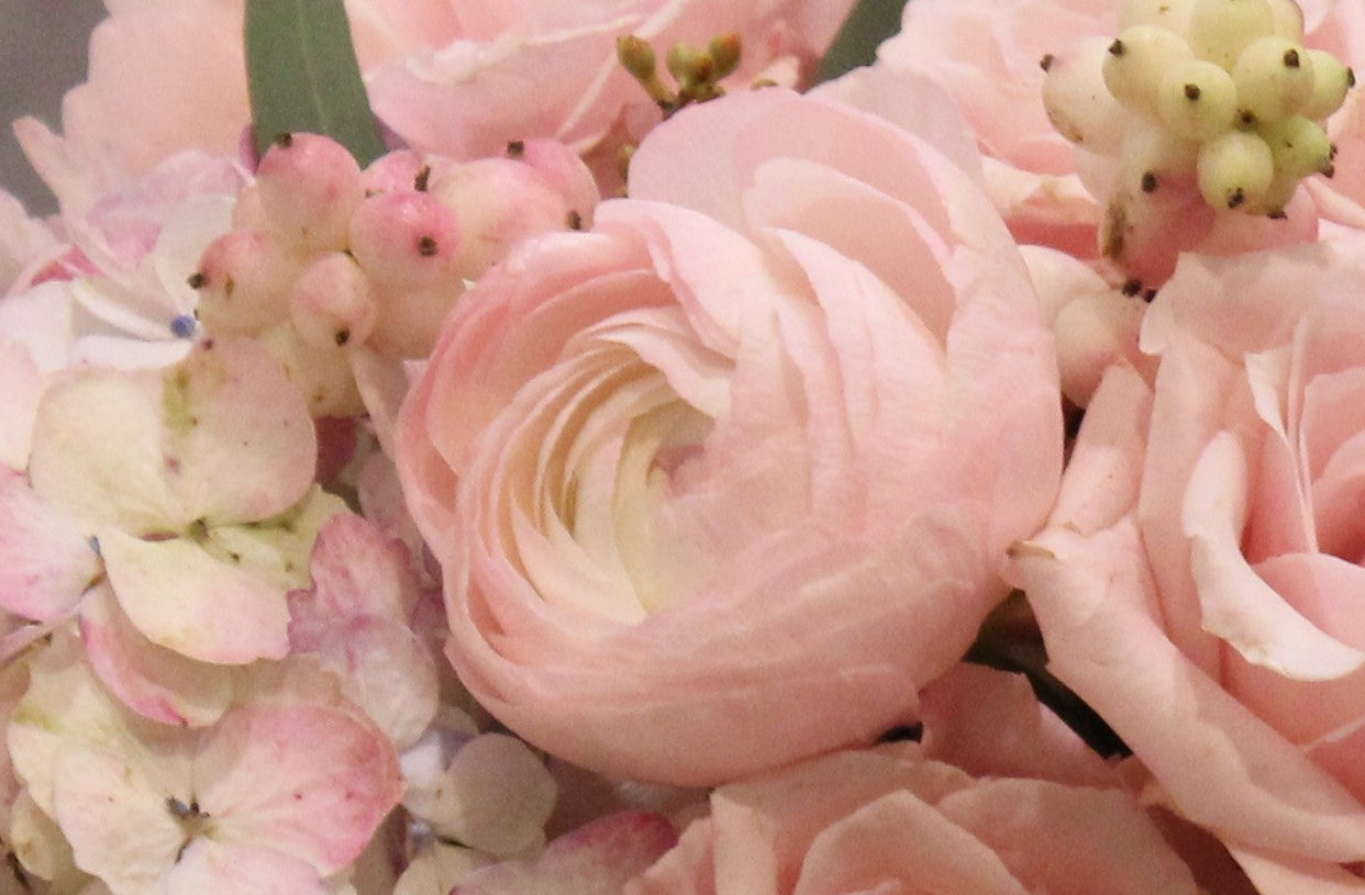 Floral arrangement in pastel pink shades with hydrangeas, pale pink roses, pink snowberries, and seeded eucalyptus 