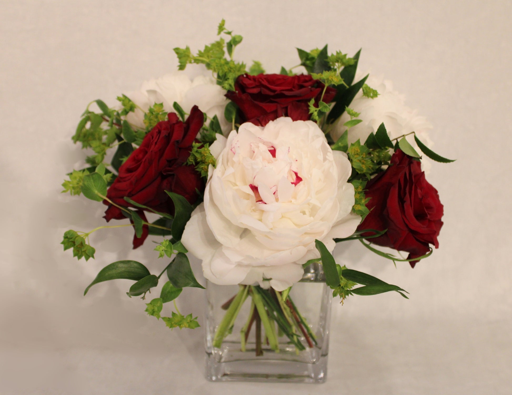 small floral arrangement in 3x4x6 glass rectangular vase with peonies, roses, and bupleurum 