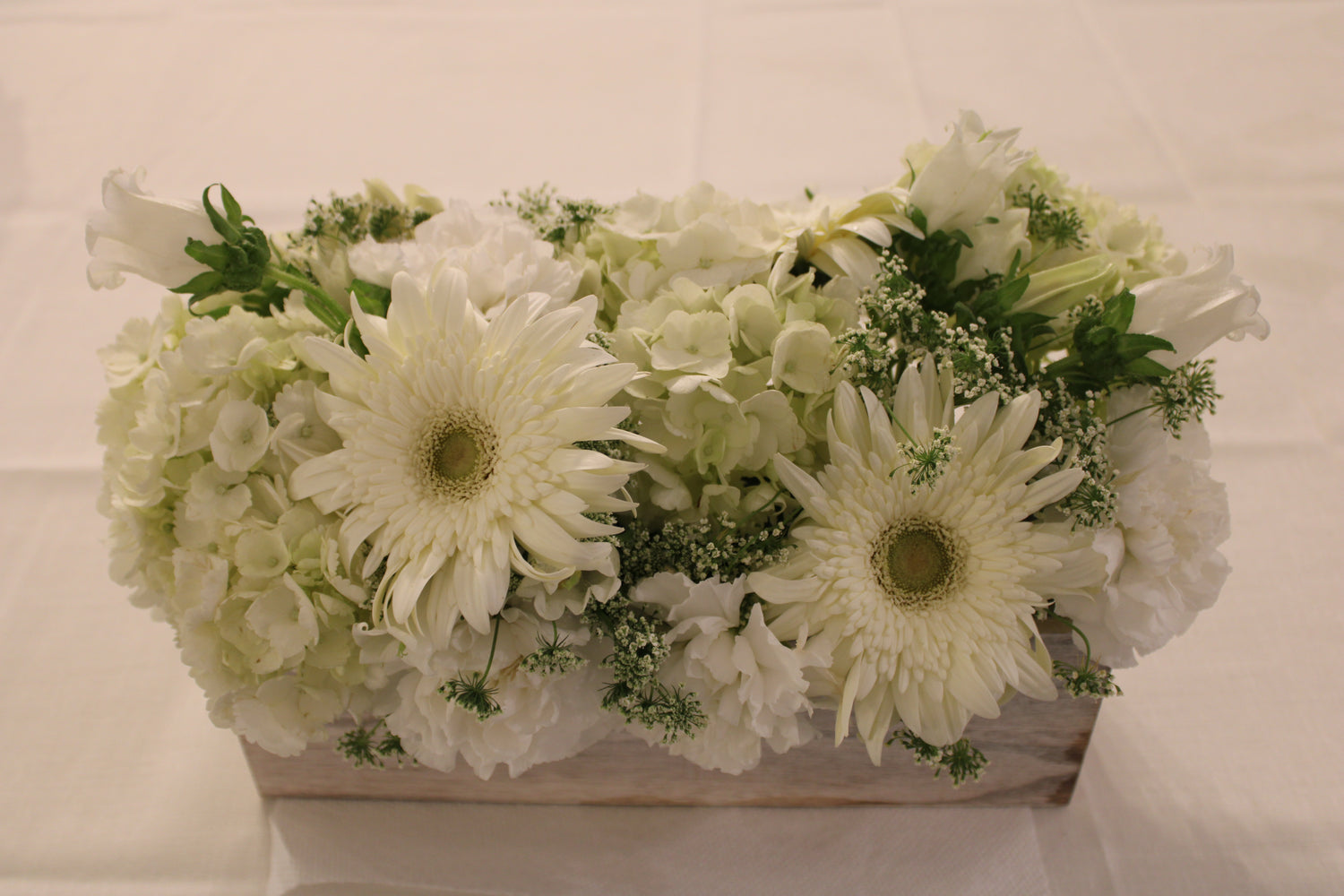 Fresh arrangement of white flowers in a rustic wooden planter 